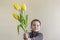 Little boy with a bouquet of yellow flowers. Boy hiding flower on his hands. Light background. European appearance.