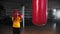 Little boy boxer walks to a punching bag and stands in front of it on position