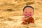 Little boy Buddhist, little Buddha, sitting on the sand on the beach . Rejoice and smiles in the Lotus position. Meditation and