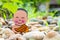 Little boy Buddhist, little Buddha, sitting on the sand on stones and green grass background. and smiles in the Lotus position.