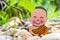 Little boy Buddhist, little Buddha, sitting on the sand on stones and green grass background. and smiles in the Lotus position.