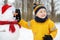 Little boy building funny snowman. Ð¡hild attaches carrot nose to snowman in snowy park