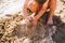 A little boy builds figures from the sand on the shore of the pond at sunset of the day, hands dig up the sand in crisp plan