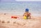 A little boy builds sand castles on the seashore.
