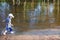 Little boy in cap and goes in water of pond