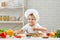 Little boy in chef hat and an apron cooking pizza