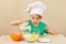 Little boy in chef hat pours milk for baking cake