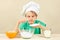 Little boy in chef hat pours sugar for baking cake