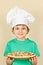 Little boy in chefs hat with cooked homemade pizza