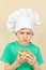 Little boy in chefs hat does not like taste of cooked pizza