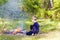 Little boy child in forest playing with bonfire.