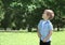 Little boy child outdoors in green sunny park looking up