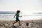 Little boy child play football on coast of sea beach. Summer kids sports.