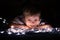 Little boy with chrismas lights lying on ground and looking at camera. Christmas lights on ground in front of boy