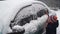 Little boy cleaning car from snow with brush. Happy child helps his pearent cleaning auto in morning after snowfall.