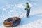 The little boy in color overalls holding in hand snow tubing