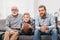 Little boy on couch with grandfather and father, cheering for a football game and holding a