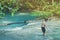 Little boy crossing a river full of stones carefully and teetering in waterfall at Erawan National Park