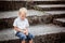 Little Boy crying sitting on stone steps in park. Loneliness, m