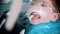 A little boy with damaged baby teeth having a treatment in the dentistry with an opening mouth guard - cleaning the