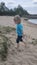 Little boy dancing on the beach. Child boy dansing on the beach. Kid is running on the bank at lake river. Boy having