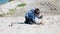 Little boy digs a hole in the sand on the beach