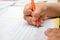 Little boy diligently writes with a pencil in his notebook.