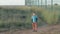 Little boy in dirty clothes standing lonely in a field near metal fence looks at the obstacle. concept feeling the emotions refuge