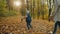 A little boy with a dog on a leash runs in the autumn park, rear view