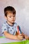 Little boy drawing with color pencils. There are many colored pencils in the boy`s hands. Small boy draws at the table