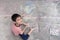 Little boy drawing and coloring by chalk on the ground art activity