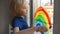 Little boy drawing on window rainbow while coronavirus quarantine. Rainbow sign is symbol of hope, means that everything will be O