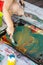 Little boy draws with hands and feet with finger paints on a large sheet at home