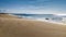 A little boy dressed in a wet suit waits for a surf wave that does not arrive, facing the ocean of Praia dos Supertubos in