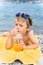 Little boy drinks juice on beach against sea