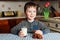 A little boy drinks milk and eats cookies in the kitchen in the morning.