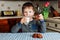 A little boy drinks milk and eats cookies in the kitchen in the morning.