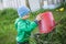 Little boy dumping a grass from a red bucket