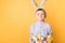 Little boy with ears of a hare holds a basket with painted eggs