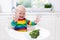 Little boy eating broccoli in white kitchen