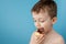 Little boy eating donut chocolate on blue background. Cute happy boy smeared with chocolate around his mouth. Child concept, tasty