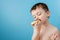 Little boy eating donut chocolate on blue background. Cute happy boy smeared with chocolate around his mouth. Child concept, tasty