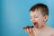 Little boy eating donut chocolate on blue background. Cute happy boy smeared with chocolate around his mouth. Child concept, tasty