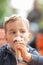 Little boy eating an ice outside in the park at a table