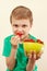 Little boy eating sweet strawberries from bowl