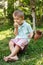 Little boy eats green apple sitting on a tree stump. Active little boy eating green apple.