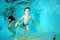The little boy is engaged in sports, swims underwater at the bottom of the pool through the Hoop.