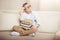 Little boy in eyeglasses sitting on sofa with pile of books and looking away