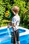 Little boy filling swimming pool with water