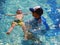 Little boy floating with swim instructor